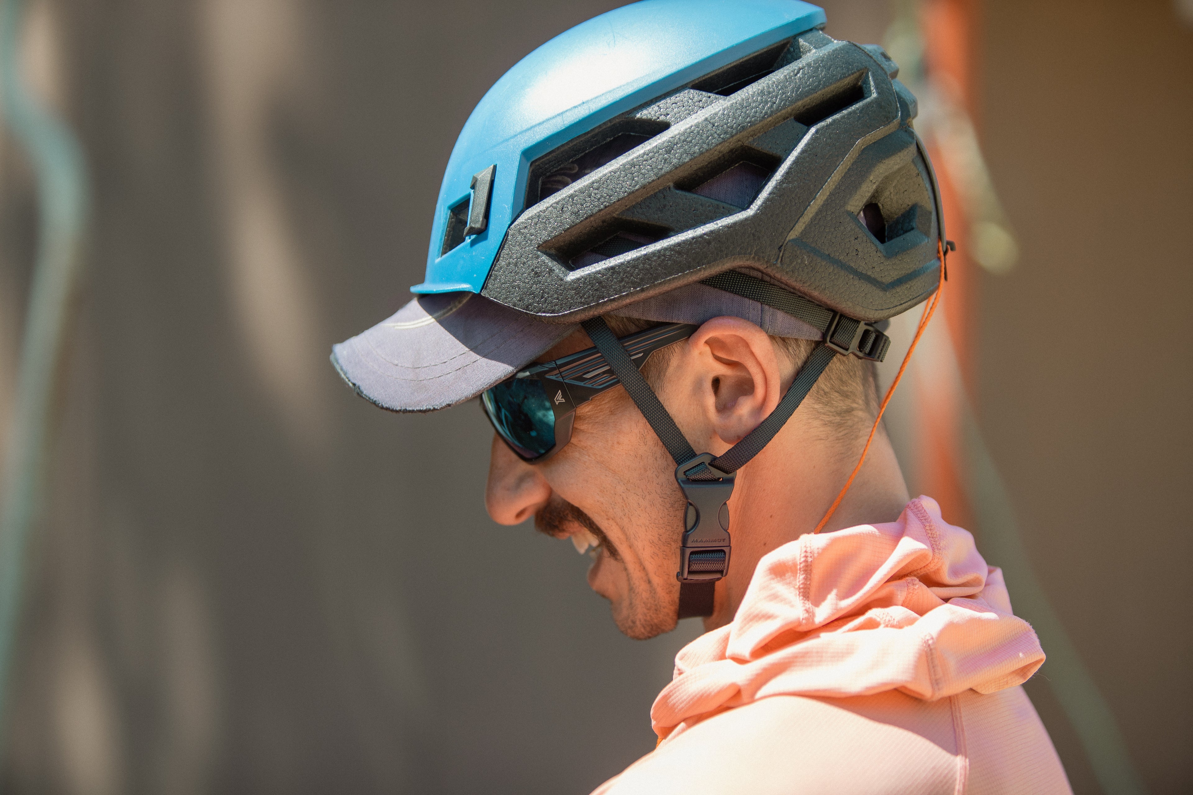 Person wearing a blue and gray helmet with safety glasses with a blurred background