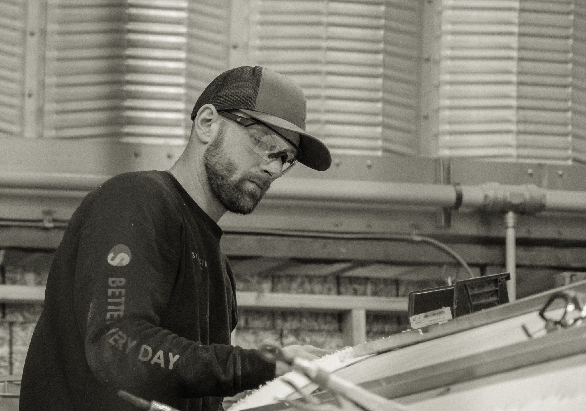 man in baseball cap wearing clear safety glasses working on a structure