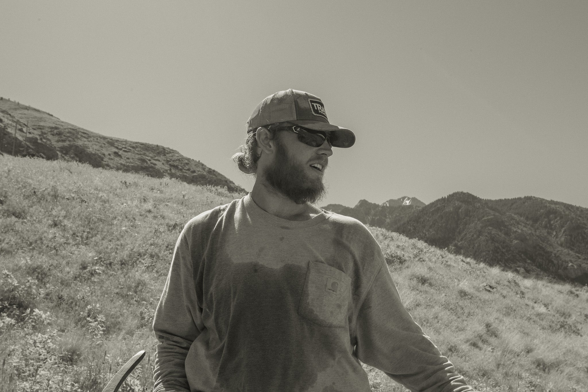man with shovel standing outdoors with safety glasses and a mountain behind him