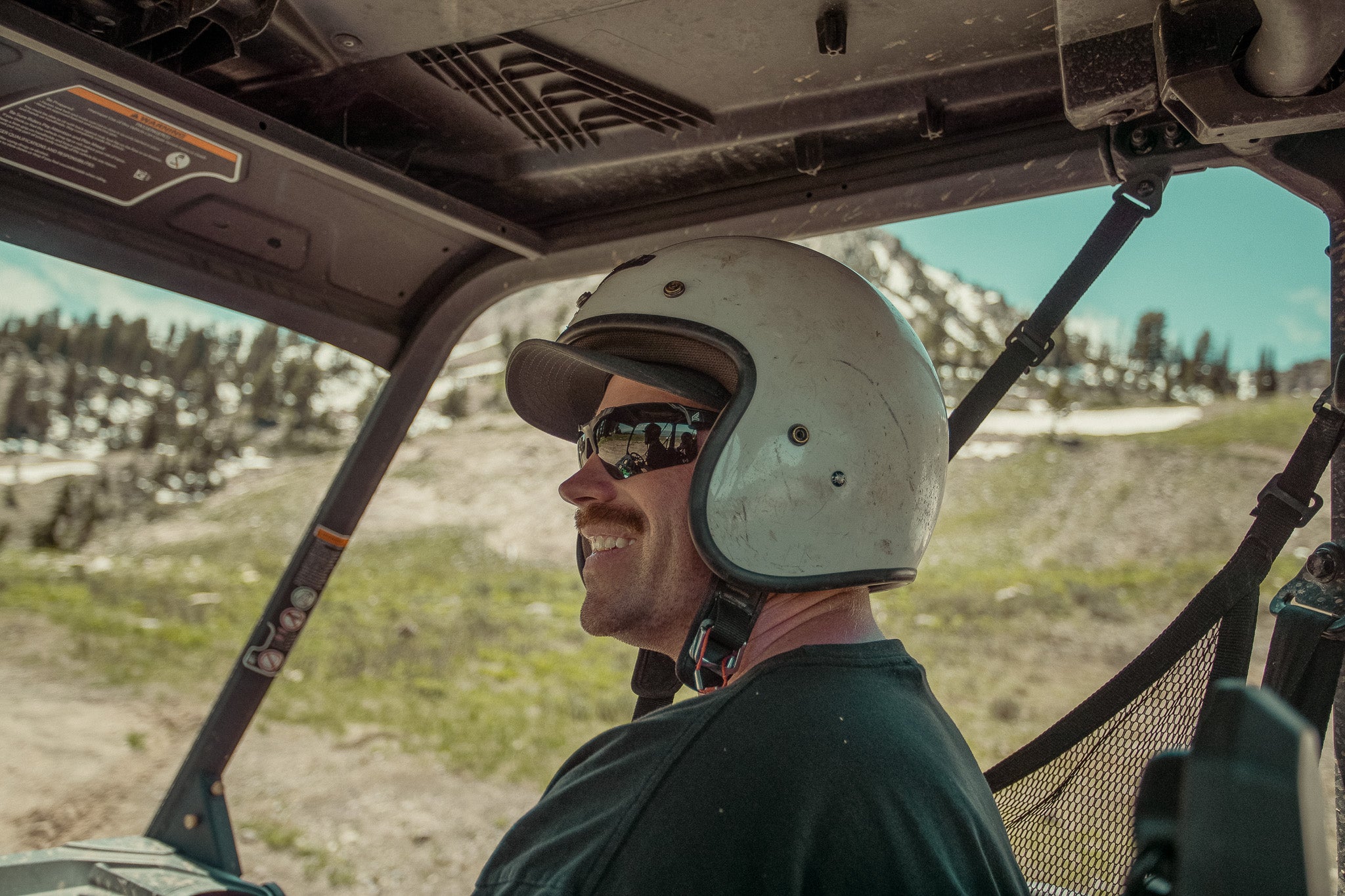 man in side by side wearing white helmet and black safety sunglasses