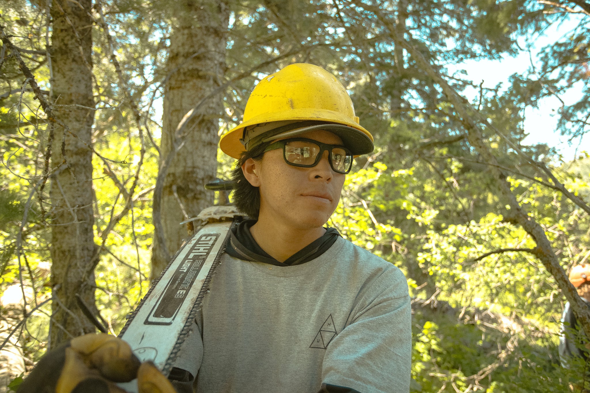 Man holding chainsaw with hard hat and safety glasses