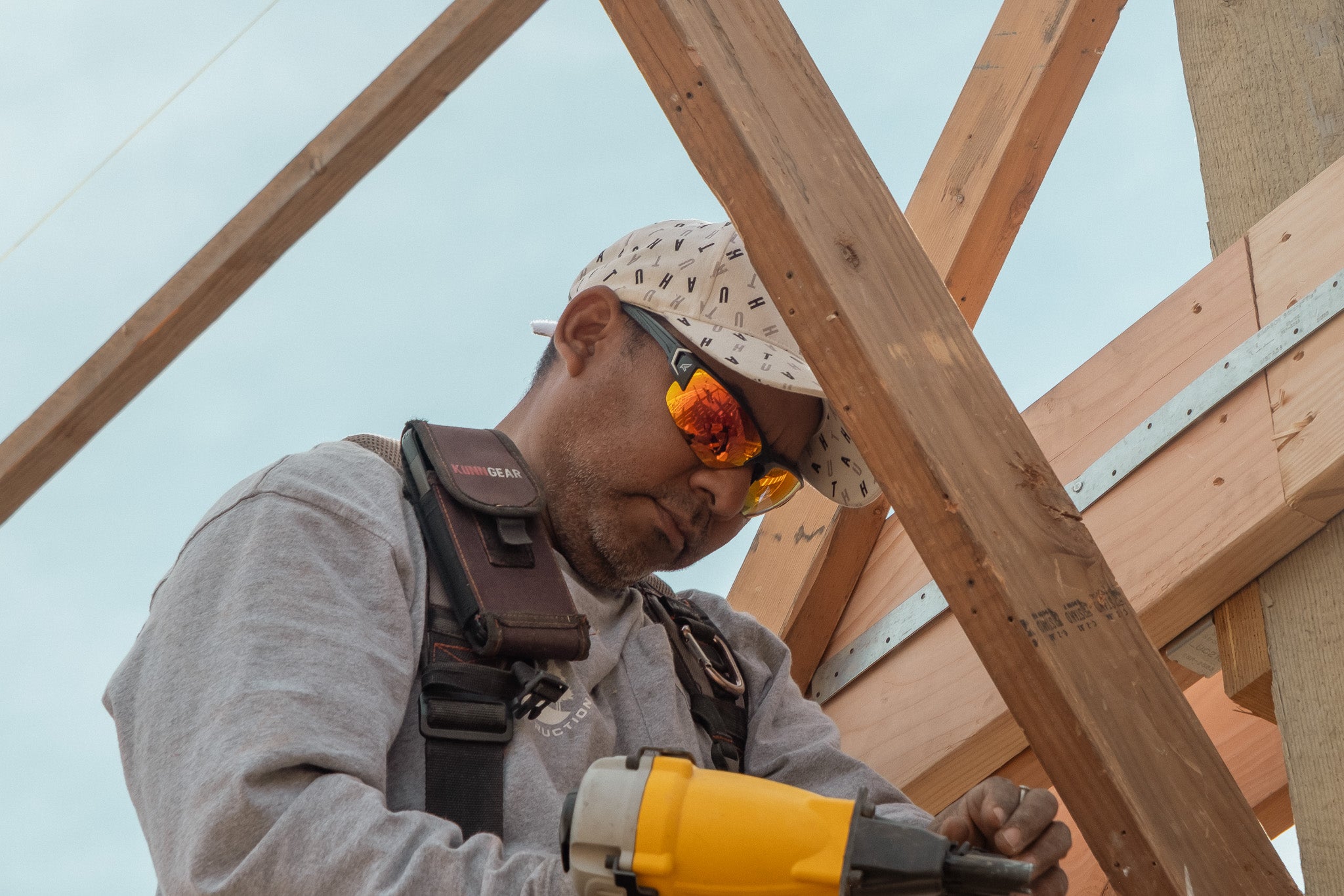 Person working on a wooden structure with tools and safety glasses