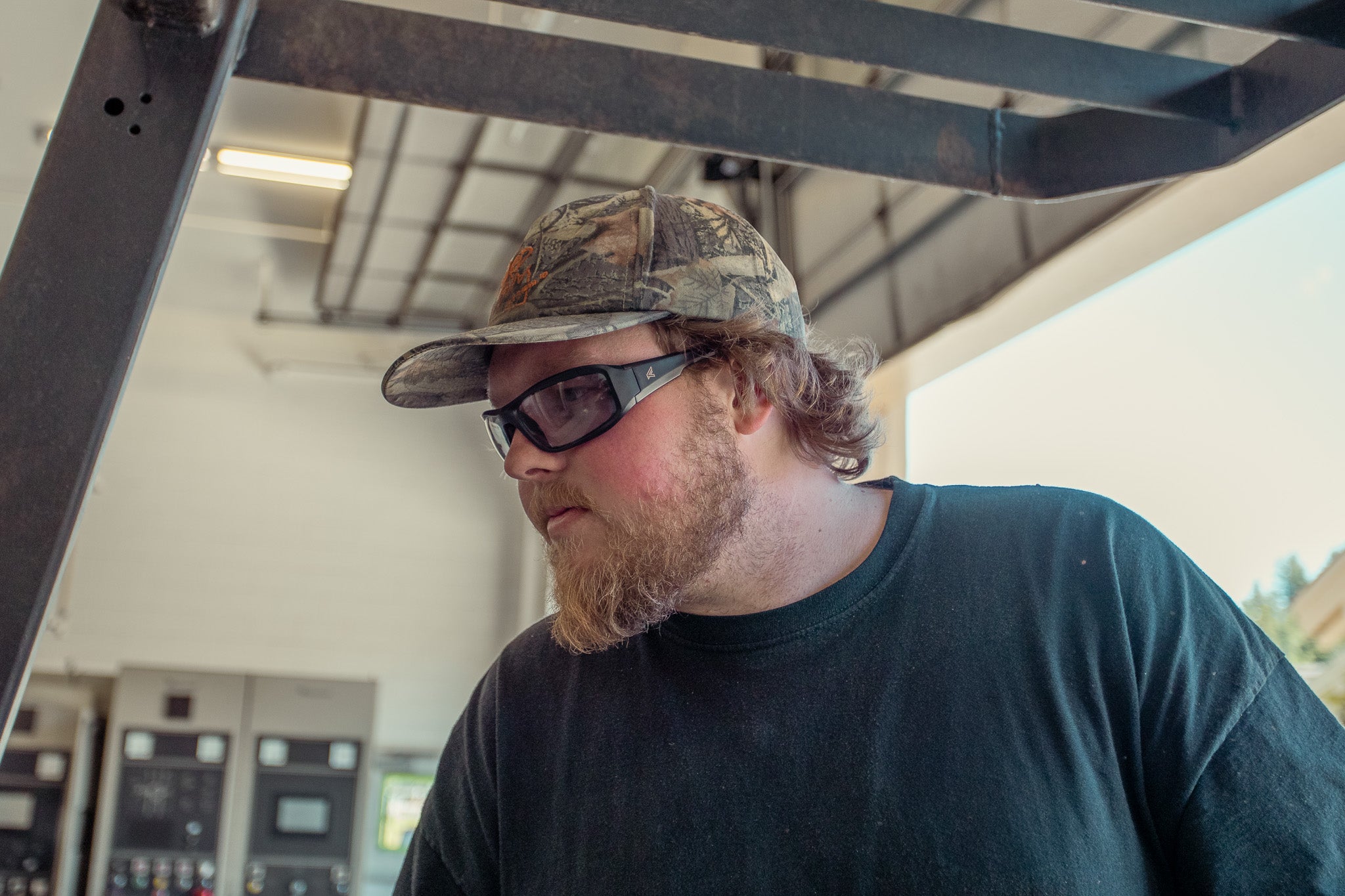 Man wearing a camouflage cap and sunglasses indoors