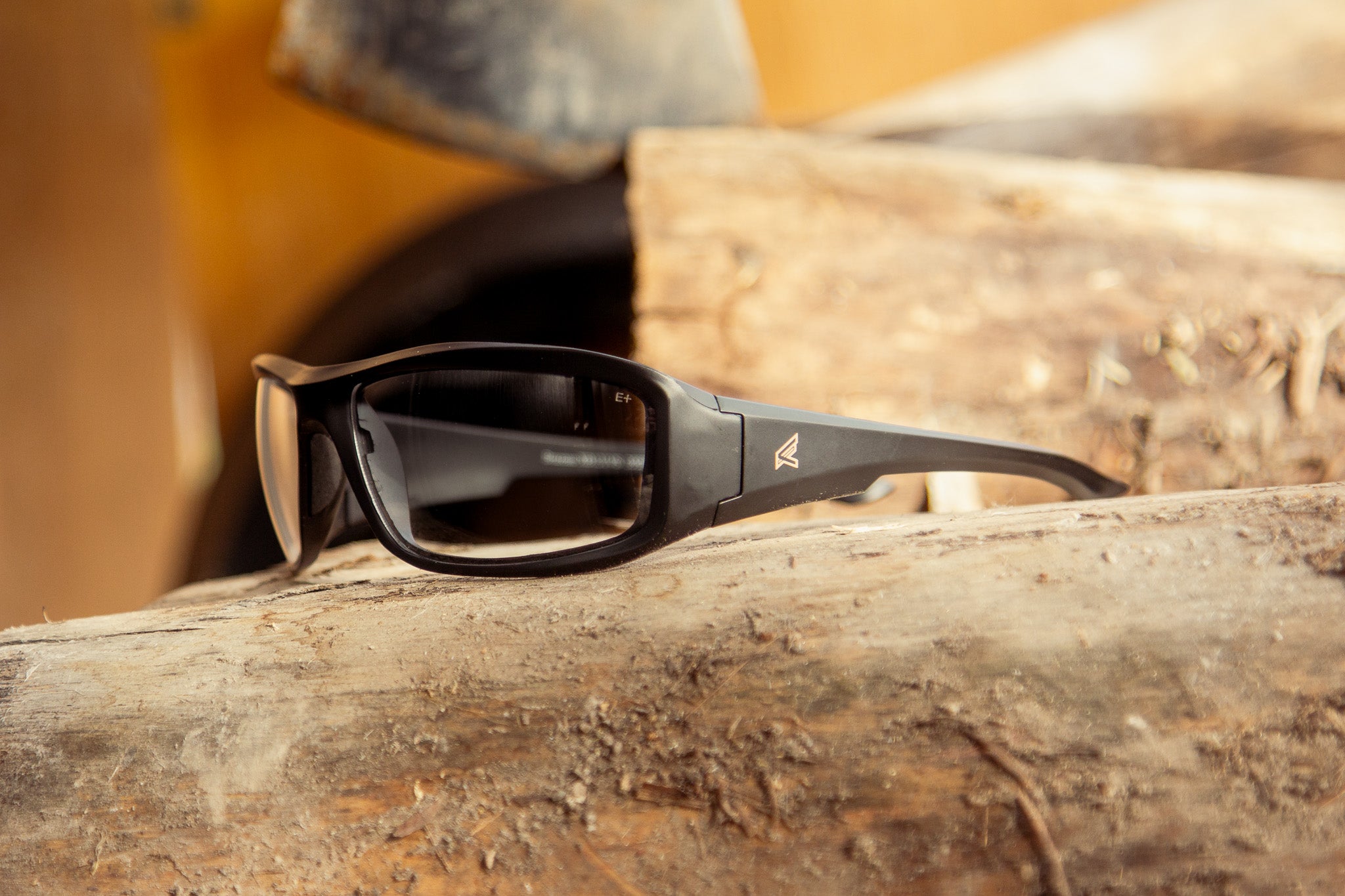 anti reflective safety glasses sitting on log with axe in the background