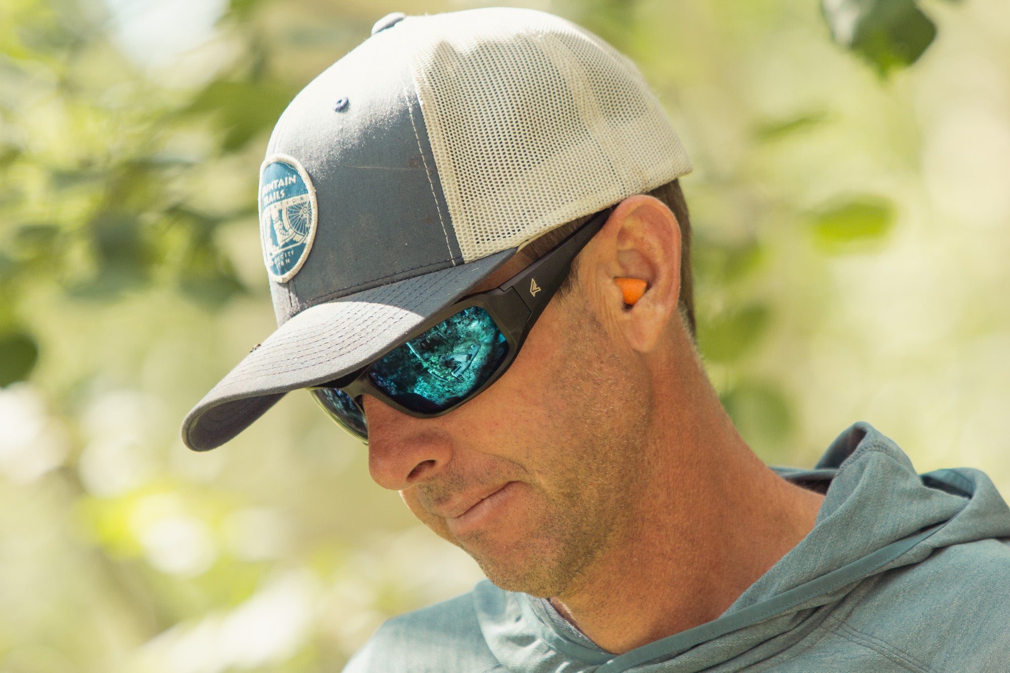 man wearing blue lens glasses with baseball cap outside