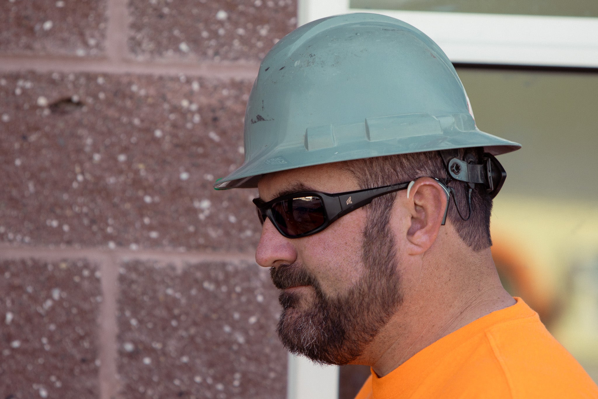man near building wearing hard hat and safety glasses working