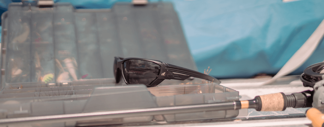 safety sunglasses sitting on tackle box with fishing equipment