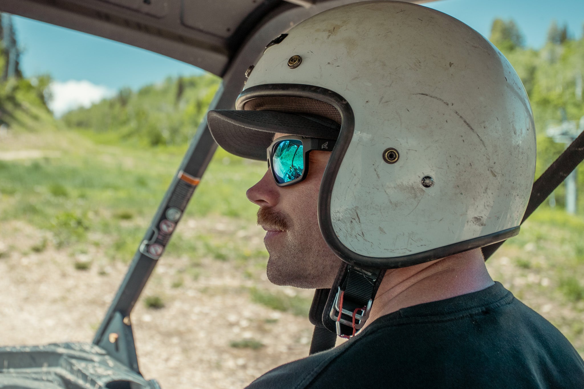 man in sxs wearing white helmet and green mirror glasses