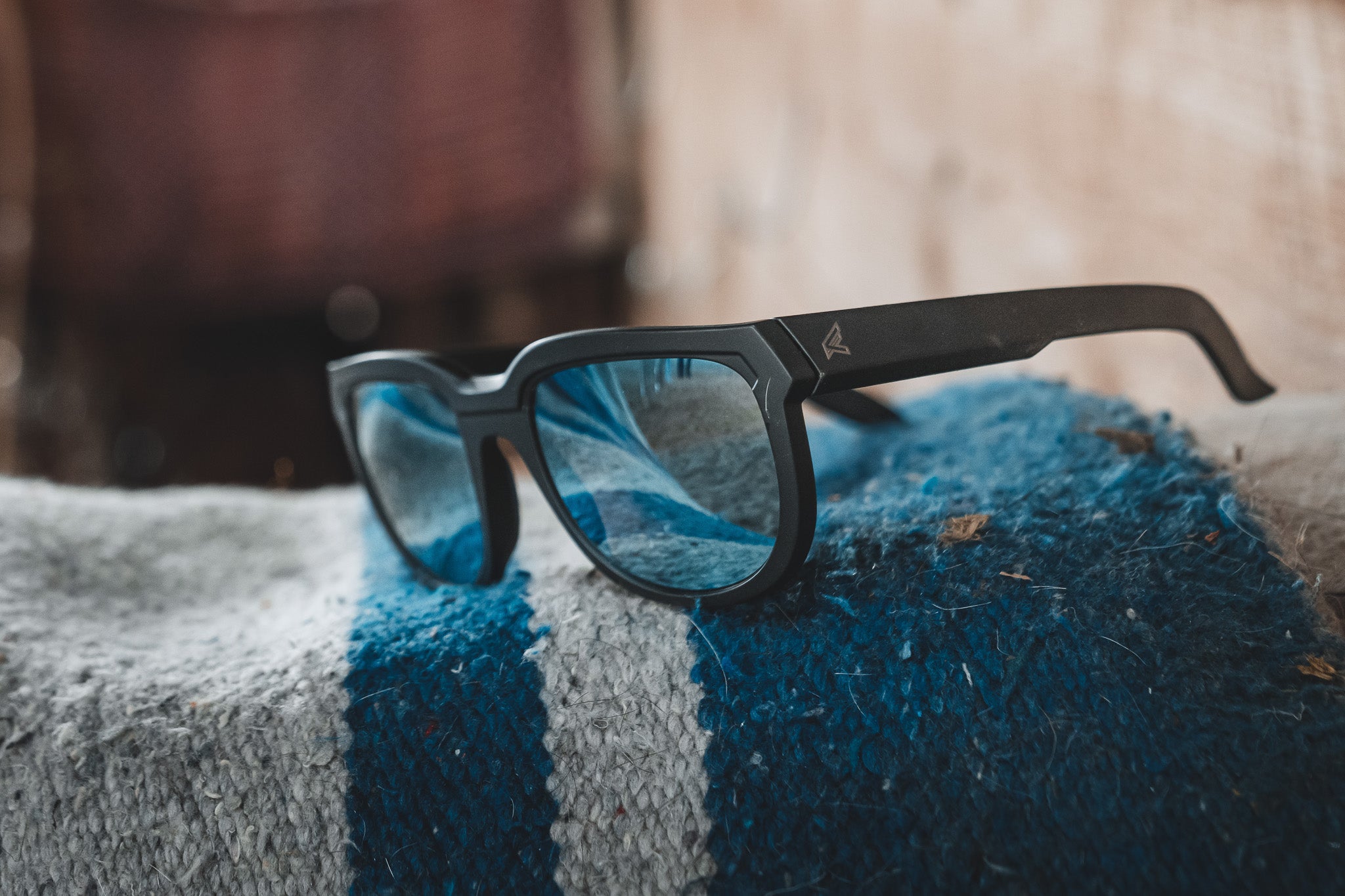 Black-framed glasses with blue lenses on a textured blue and gray surface