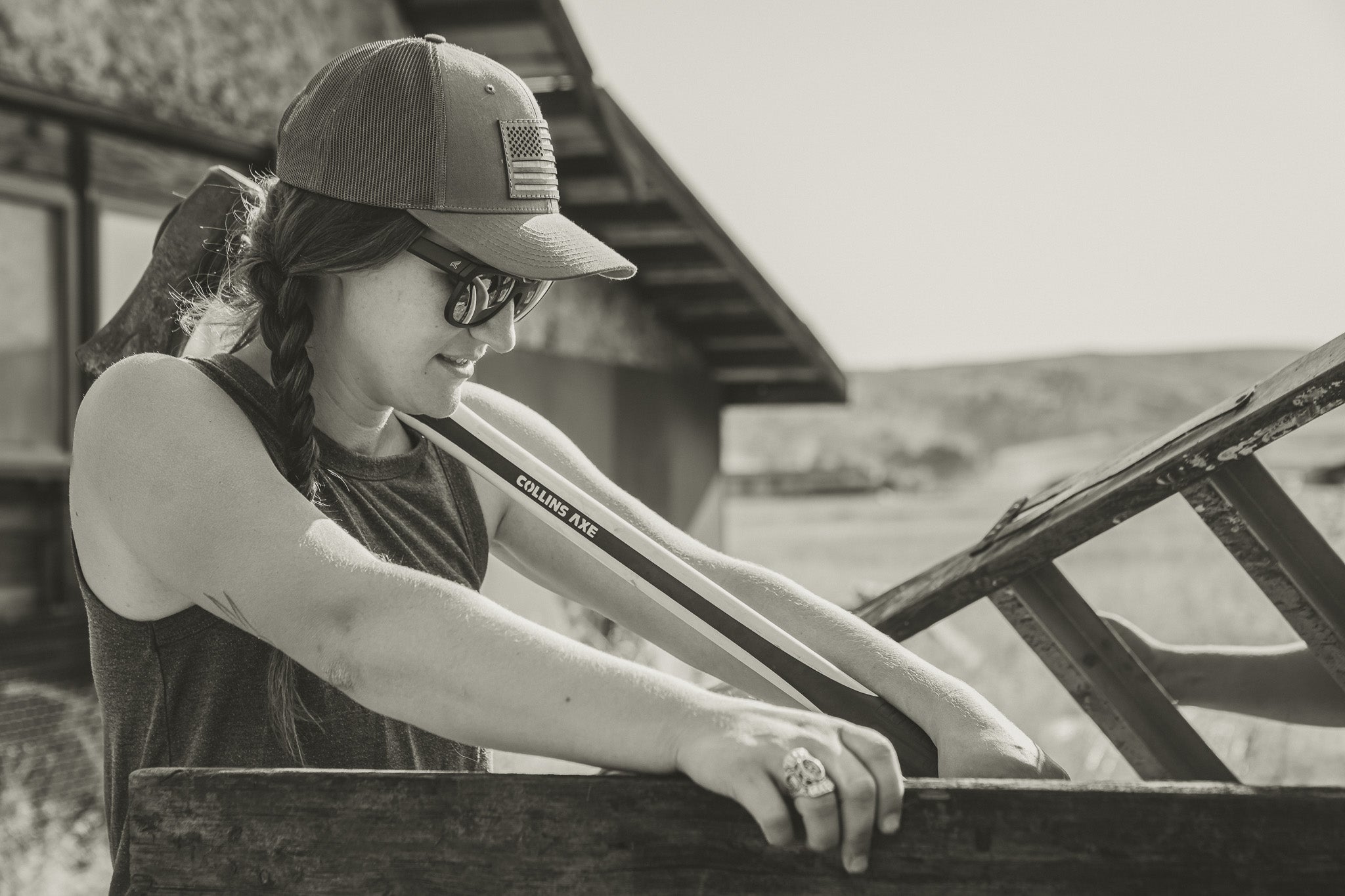 woman wearing a baseball cap and sunglasses loading an axe in a truck