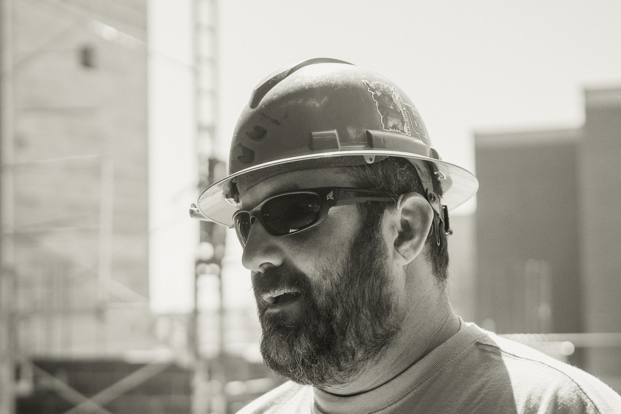 Black and white photo of a construction worker wearing a hard hat and sunglasses.