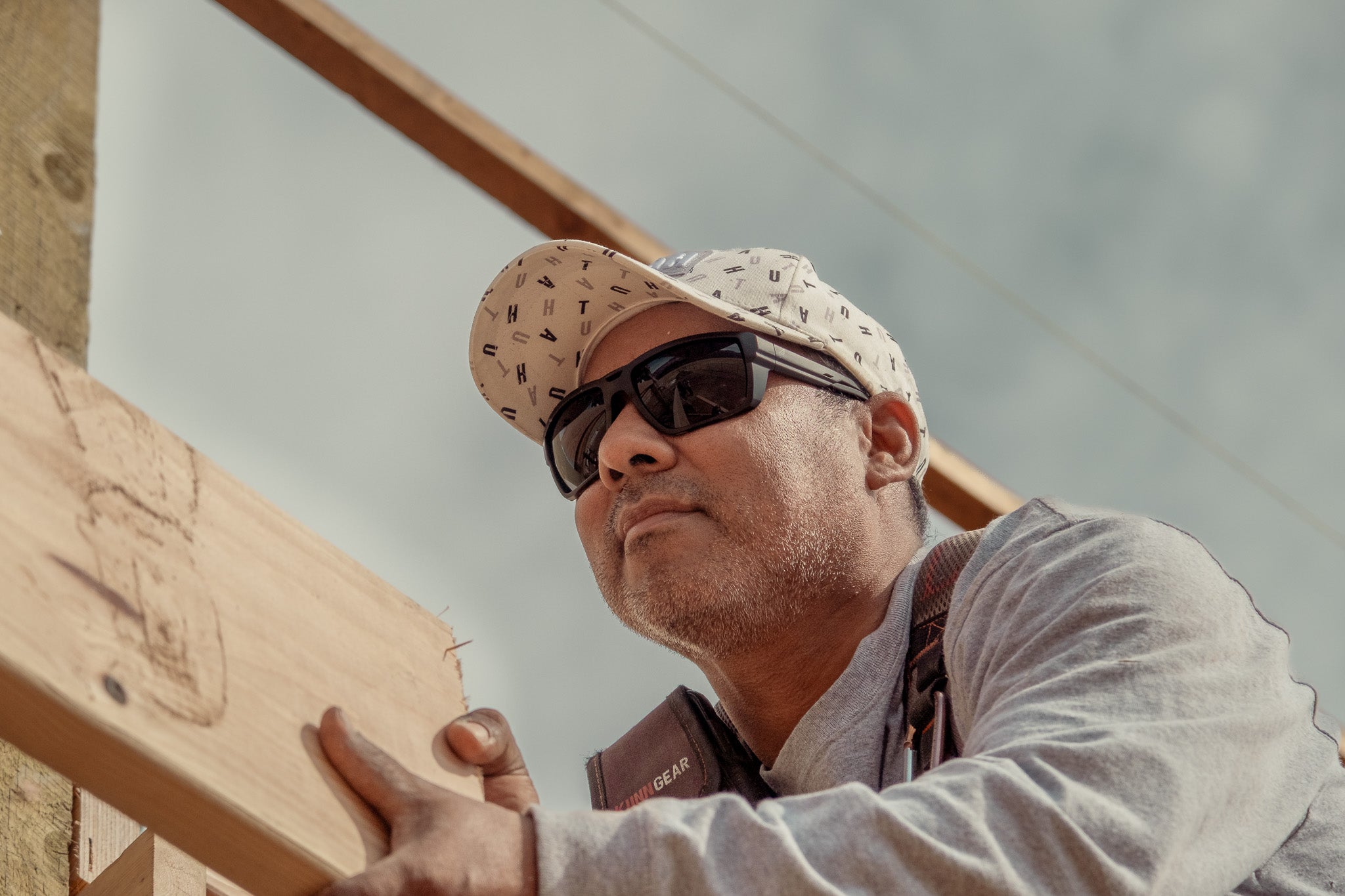 Man wearing safety sunglasses holding wooden planks outdoors