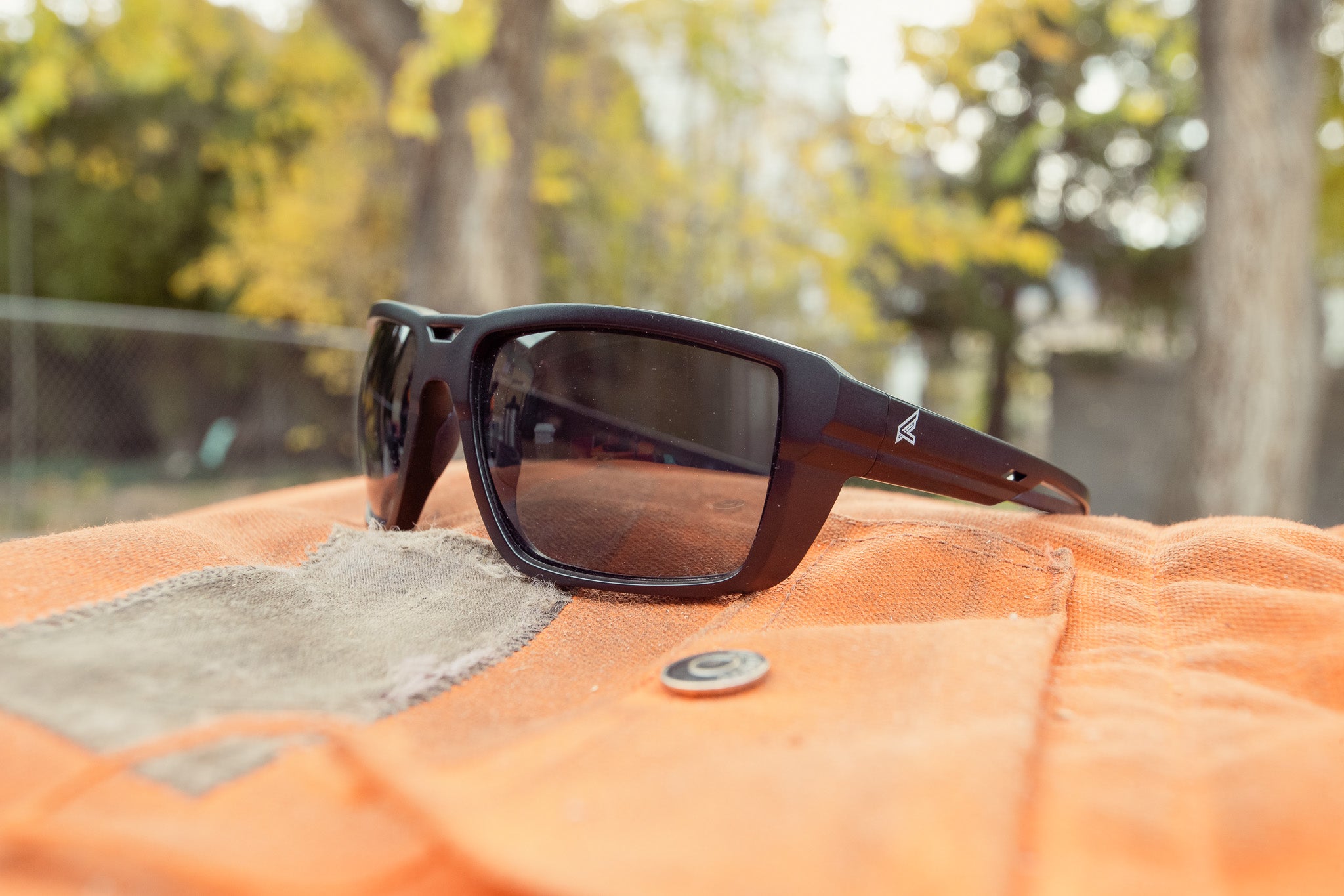 Sunglasses on an orange surface with a blurred natural background