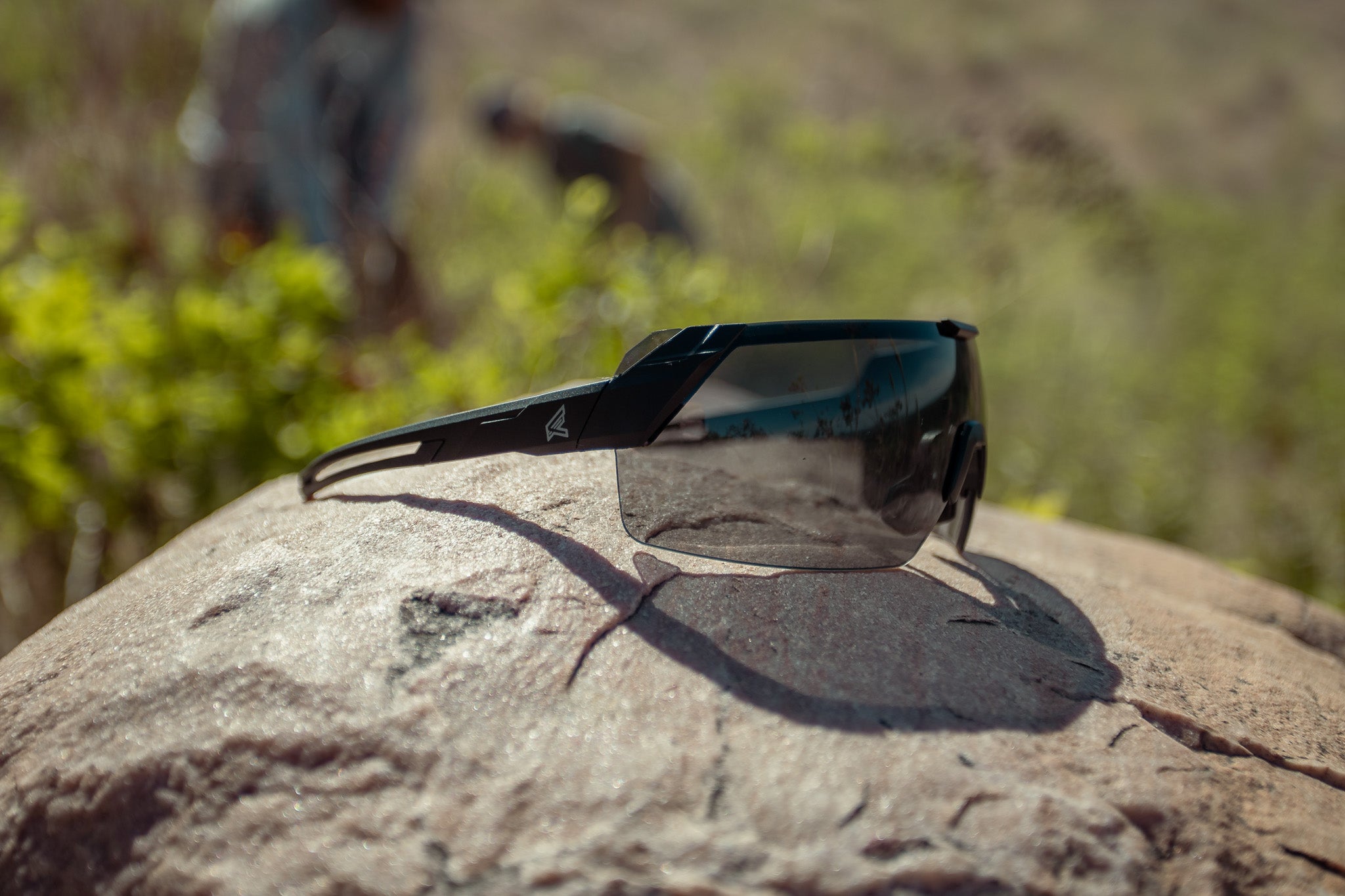 sunglasses sitting on a rock in an outdoor environment