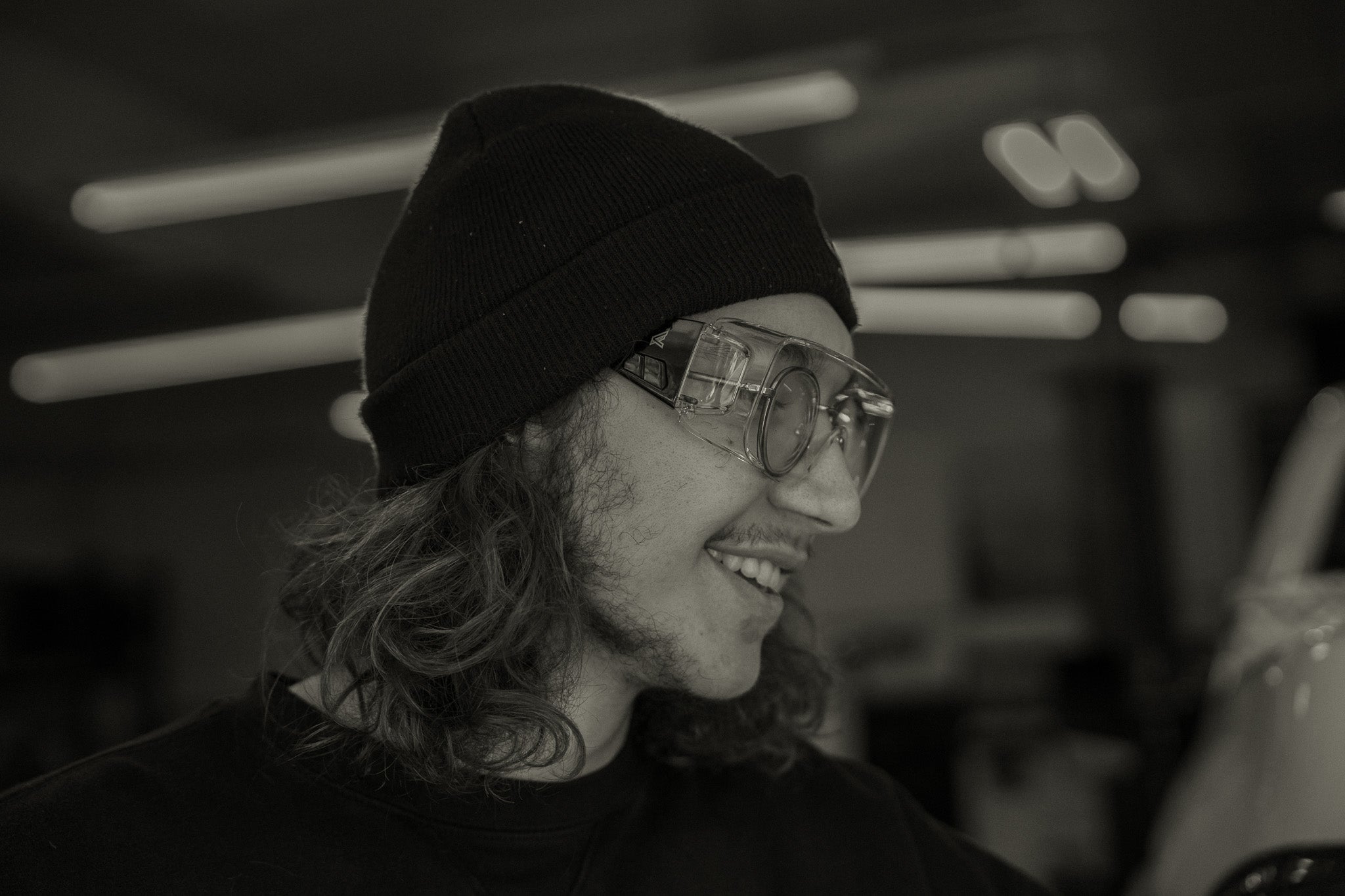 Person wearing a beanie and over-glasses safety glasses with a blurred background