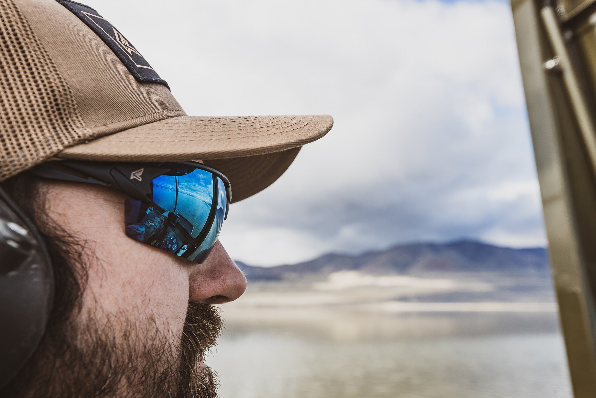 man wearing hat and blue mirror lens safety glasses outdoors 