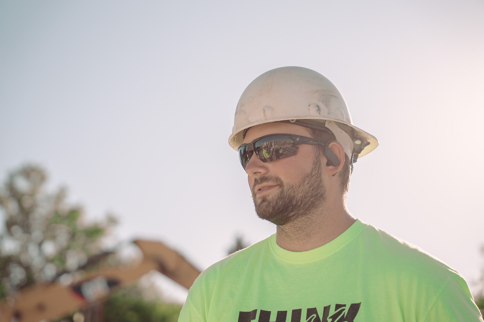 man on job site wearing hard hat and tinted safety glasses