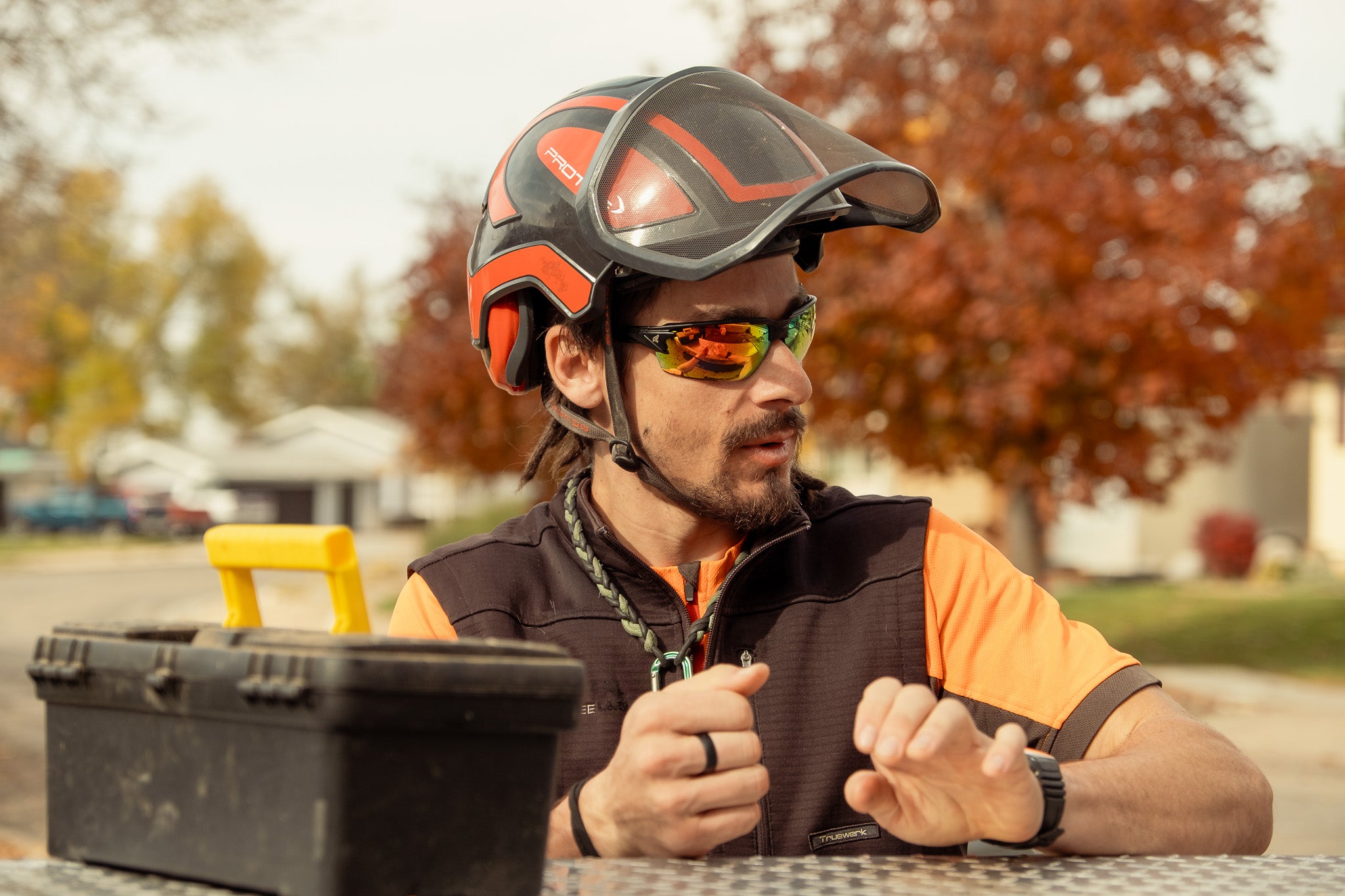 man wearing arbor helmet and safety glasses with red lenses at truck
