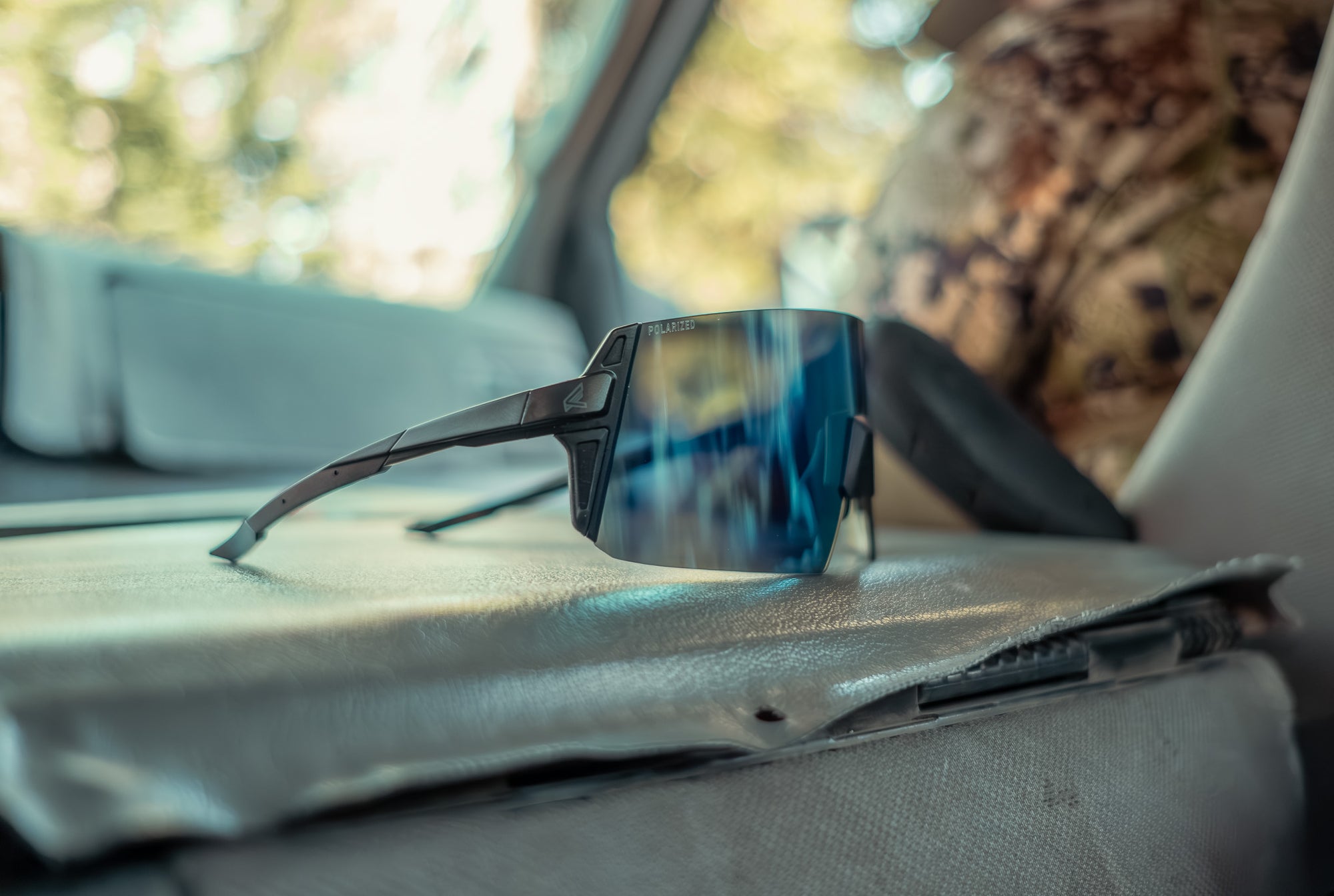 Sunglasses on a car dashboard with a blurred outdoor background