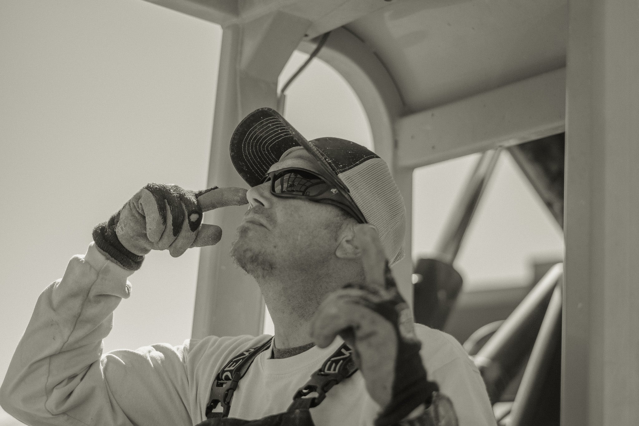 man with baseball cap and safety glasses with polarized lenses operating machinery