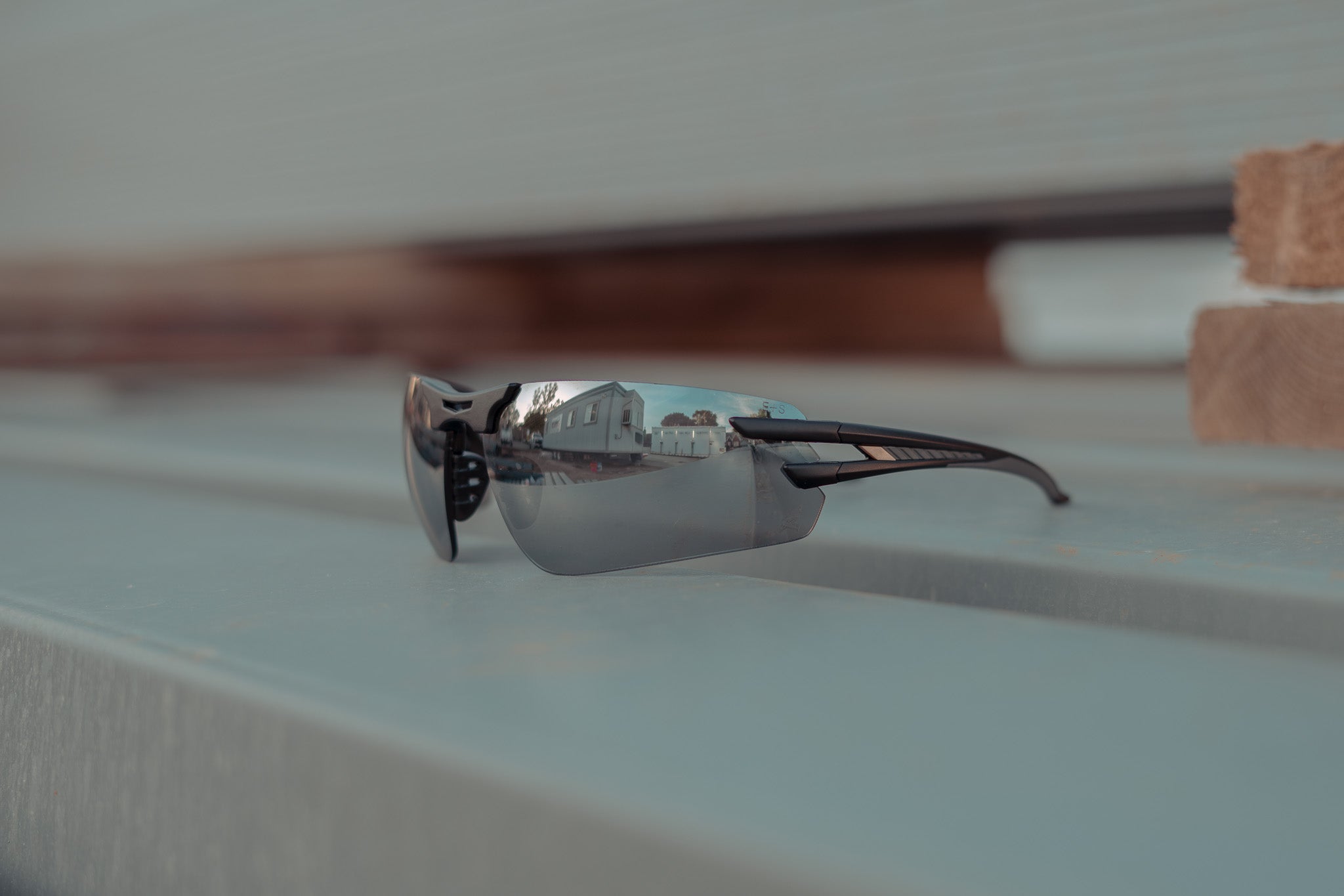 Silver sunglasses on a reflective surface with blurred background