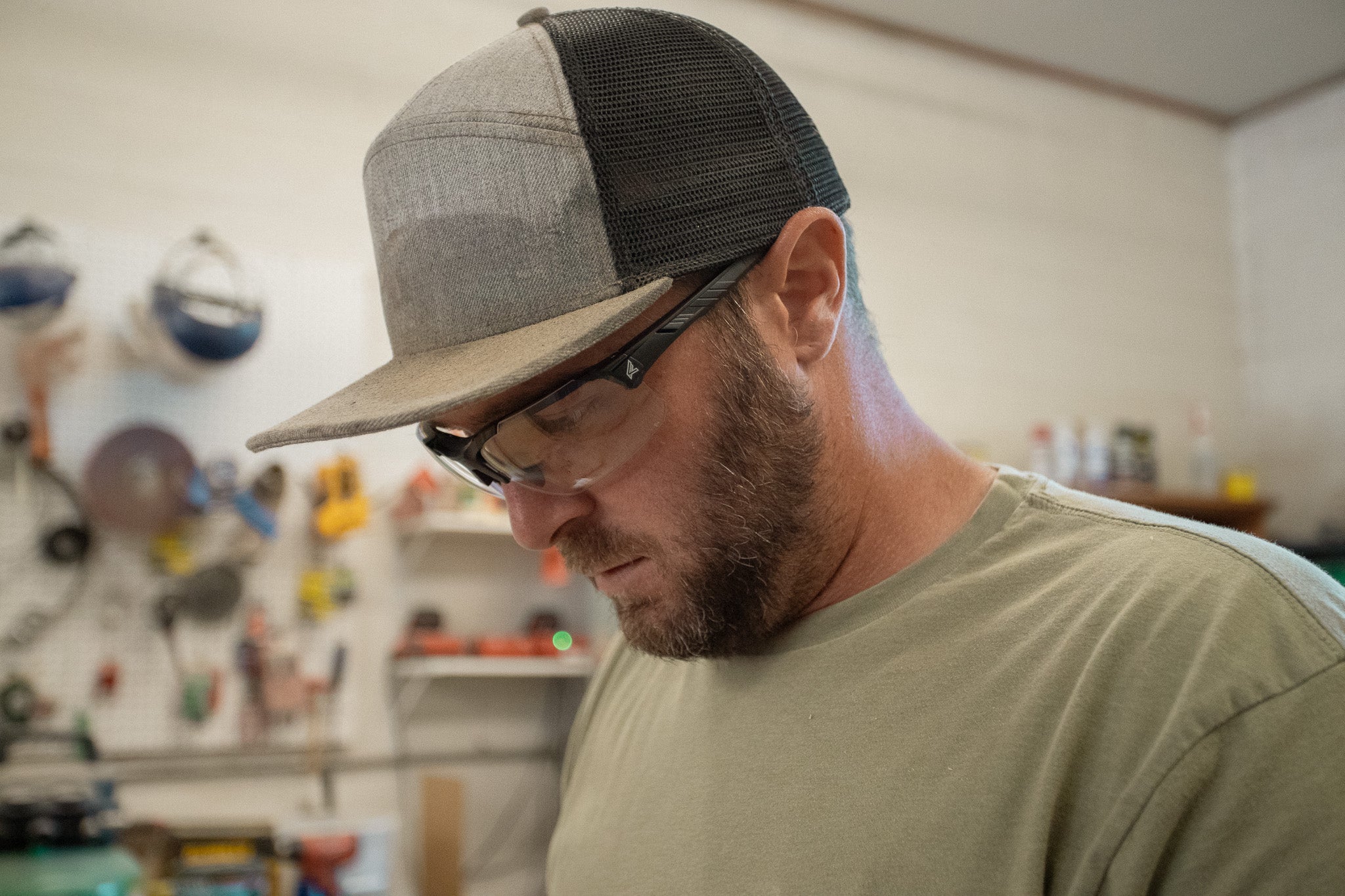 Man wearing a cap and safety glasses in a workshop setting