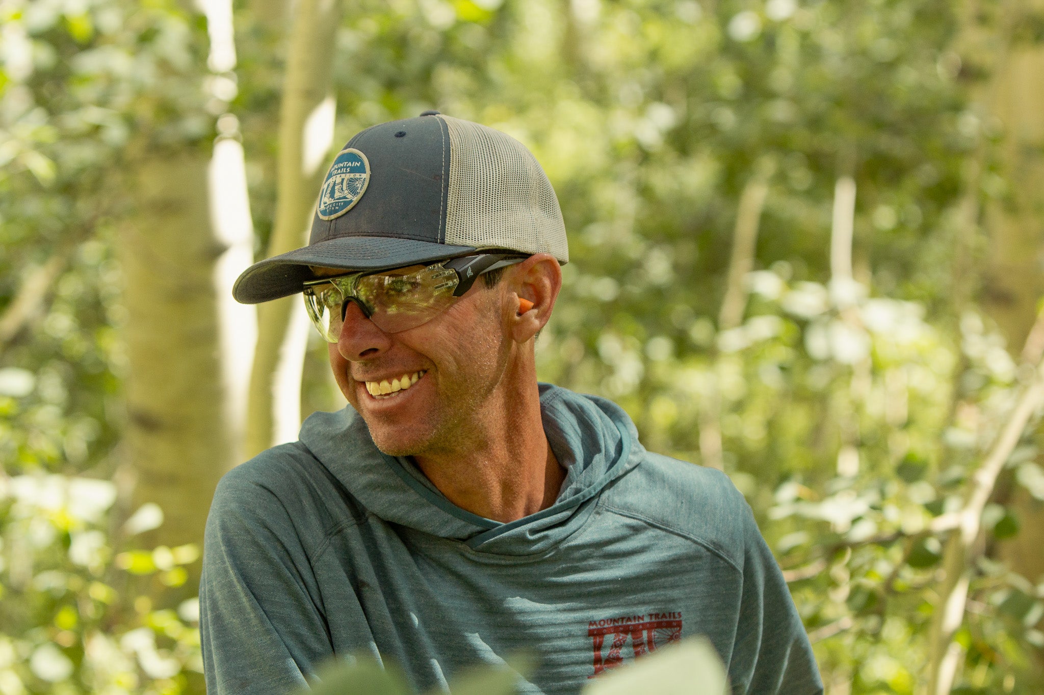 man wearing baseball cap and safety glasses in outdoor environment 