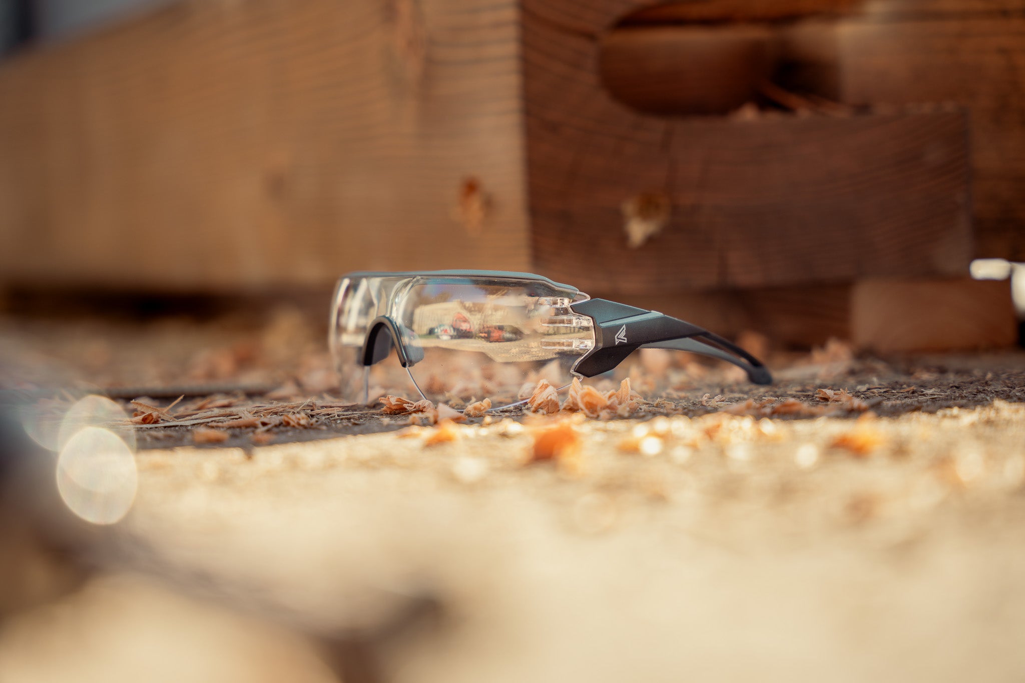 Safety glasses on a wooden surface with sawdust
