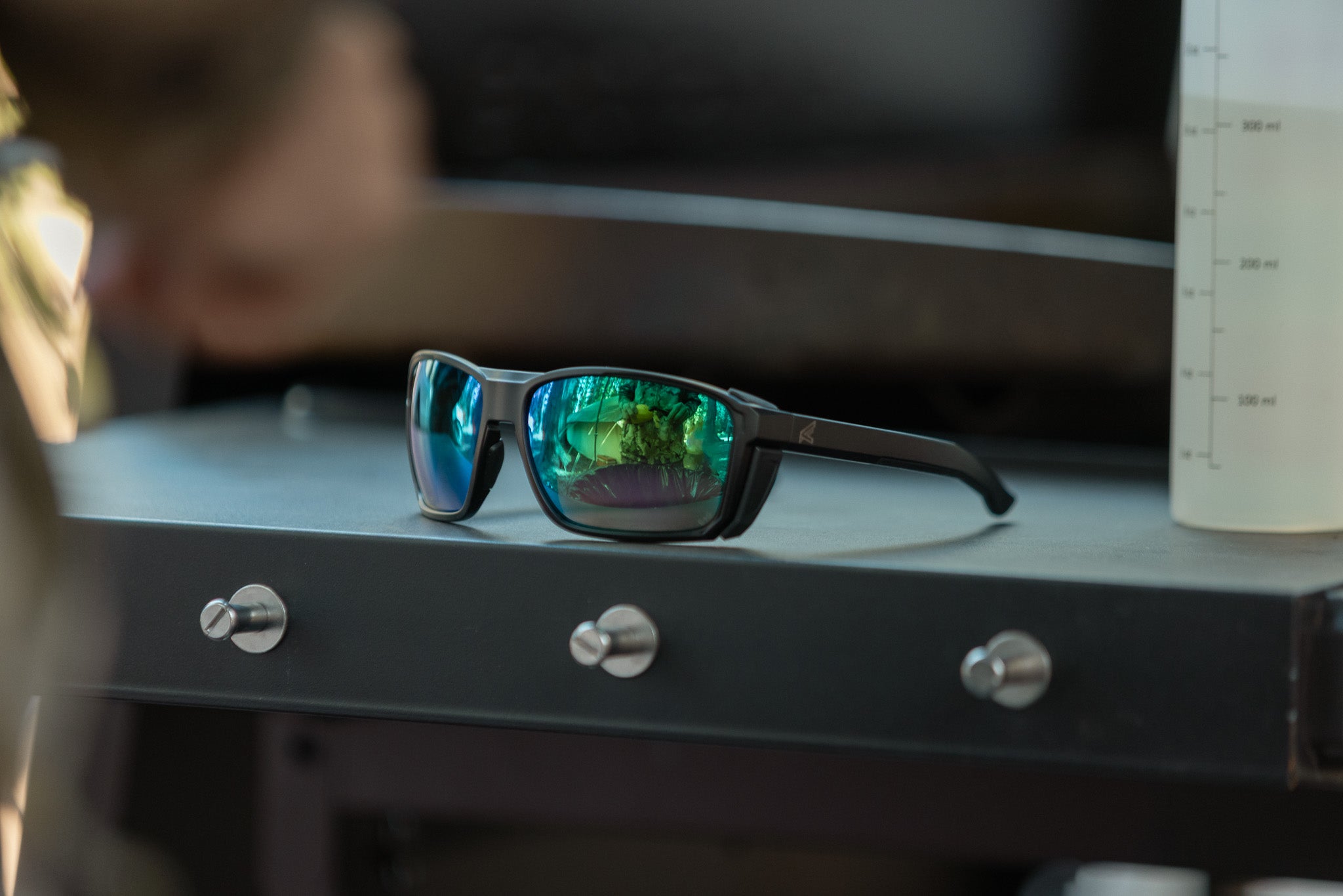 Sunglasses with reflective lenses on a metallic surface with blurred background